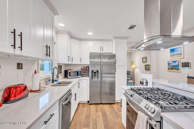 kitchen featuring sink, appliances with stainless steel finishes, island range hood, and white cabinetry