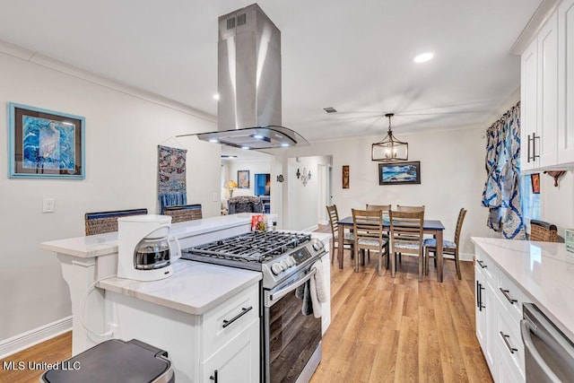 kitchen with appliances with stainless steel finishes, pendant lighting, white cabinetry, and island range hood