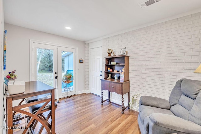 sitting room with light hardwood / wood-style flooring, french doors, and brick wall