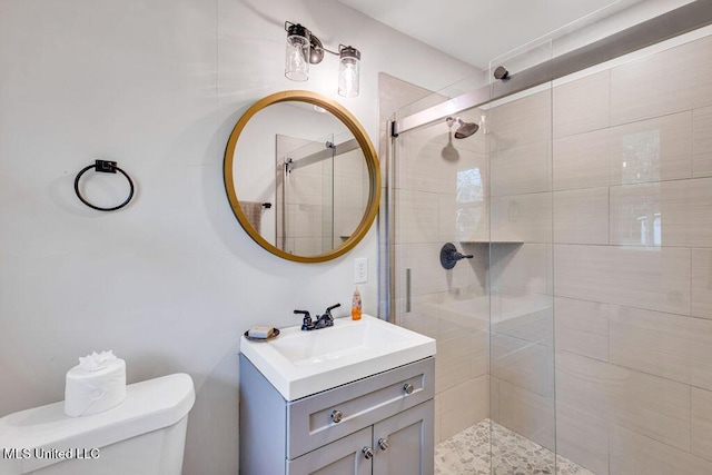 bathroom featuring toilet, a shower with door, and vanity