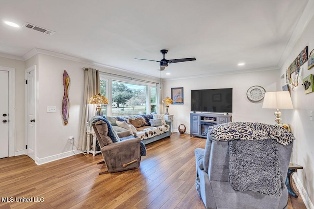 living room featuring hardwood / wood-style flooring, ceiling fan, and crown molding