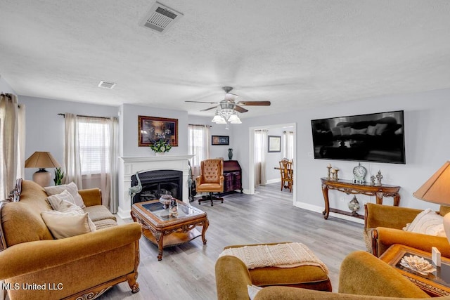 11020 Jordan Dr, Bay Saint Louis, MS 39520 - living room with a textured ceiling, a ceiling fan, light wood finished floors, a fireplace, and baseboards