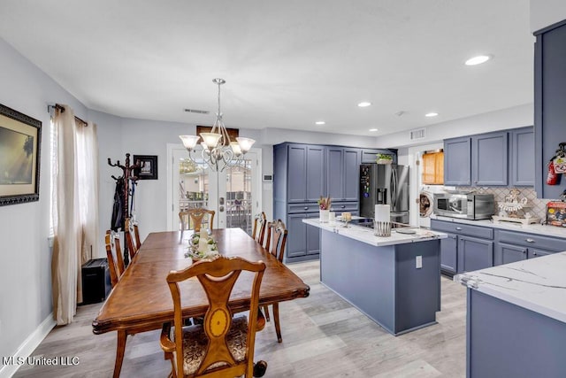 11020 Jordan Dr, Bay Saint Louis, MS 39520 - kitchen featuring stainless steel appliances, a chandelier, a kitchen island, light stone counters, and decorative backsplash