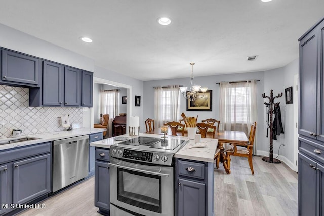 11020 Jordan Dr, Bay Saint Louis, MS 39520 - kitchen featuring stainless steel appliances, a chandelier, light wood-type flooring, backsplash, and pendant lighting