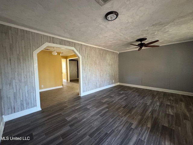 spare room featuring ceiling fan, dark wood-type flooring, crown molding, a textured ceiling, and wooden walls