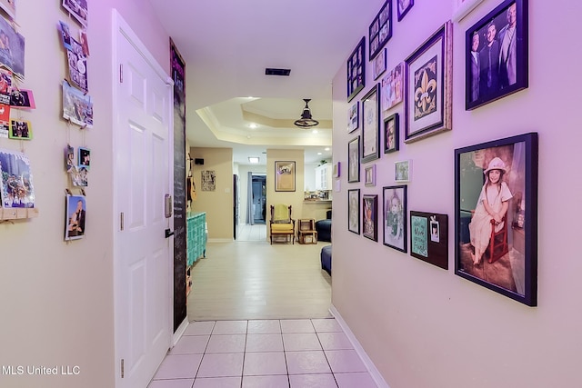 hallway with a tray ceiling and light hardwood / wood-style flooring