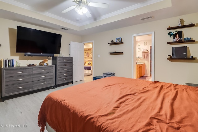 bedroom featuring connected bathroom, a tray ceiling, ceiling fan, and crown molding