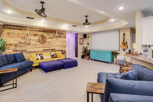 home theater featuring light wood-type flooring, a raised ceiling, and wood walls