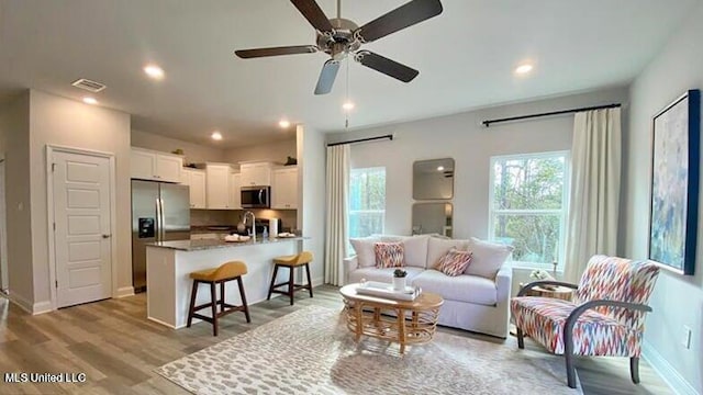 living room featuring light hardwood / wood-style floors, sink, and ceiling fan