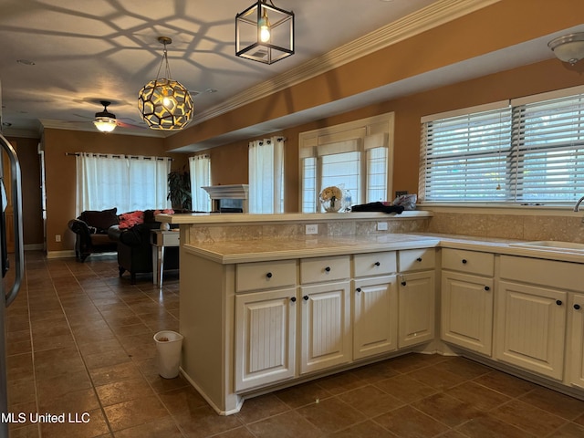 kitchen featuring decorative light fixtures, ceiling fan, kitchen peninsula, and sink