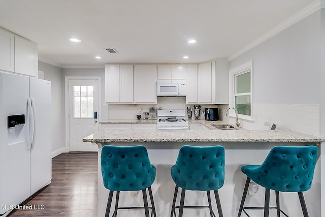 kitchen featuring white appliances, white cabinets, kitchen peninsula, and sink