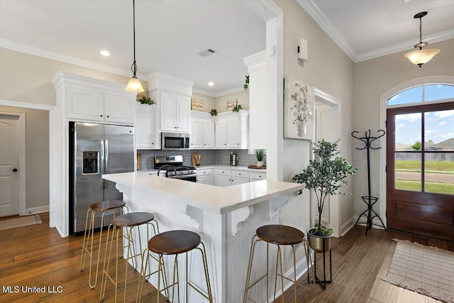 142 Western Ridge Cir, Canton, MS 39046 - kitchen featuring appliances with stainless steel finishes, white cabinets, light countertops, backsplash, and ornamental molding
