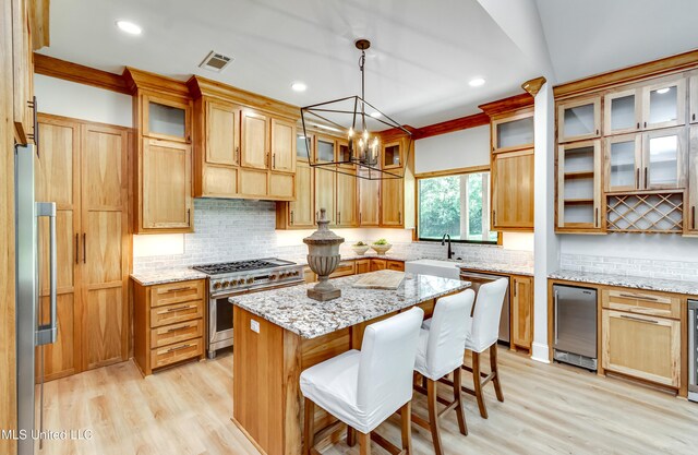 106 Horseshoe Ln, Flora, MS 39071 - kitchen with appliances with stainless steel finishes, a sink, light wood-type flooring, a kitchen island, and backsplash