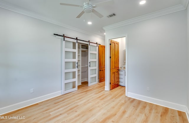 106 Horseshoe Ln, Flora, MS 39071 - unfurnished bedroom featuring light wood-type flooring, crown molding, a spacious closet, a barn door, and baseboards