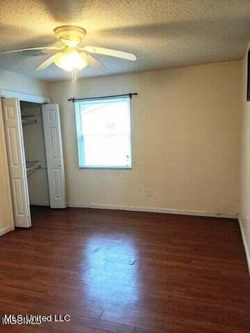 unfurnished bedroom featuring dark hardwood / wood-style flooring, ceiling fan, a closet, and a textured ceiling