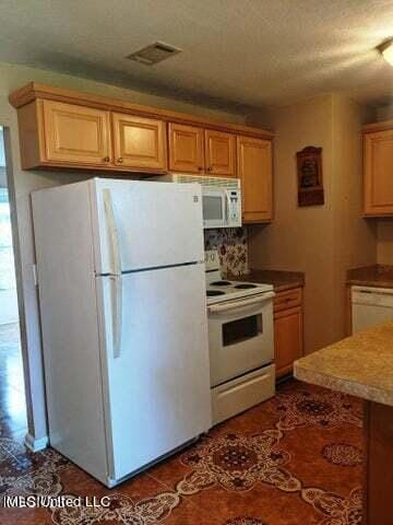 kitchen featuring white appliances, a textured ceiling, and tasteful backsplash