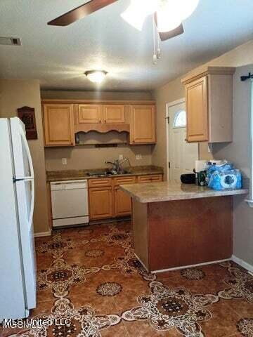 kitchen with light brown cabinetry, sink, and white appliances