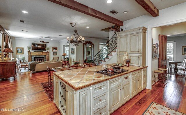 338 Hillview Dr, Ridgeland, MS 39157 - kitchen with stainless steel gas stovetop, tile counters, hanging light fixtures, cream cabinets, and beamed ceiling