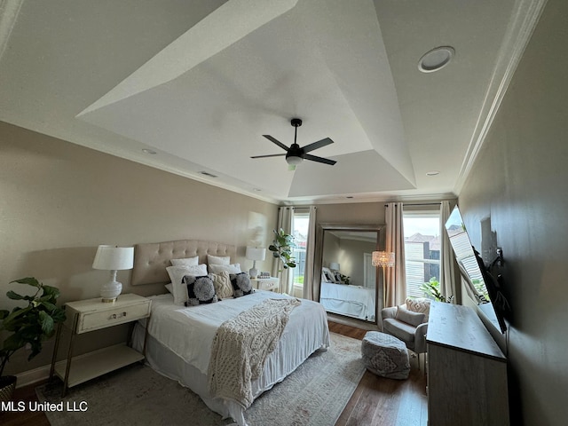 bedroom with ceiling fan, crown molding, a tray ceiling, and dark hardwood / wood-style flooring