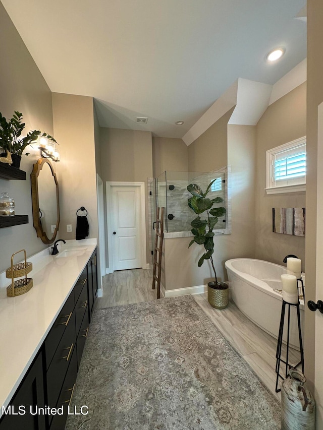 bathroom with vanity, hardwood / wood-style flooring, lofted ceiling, and plus walk in shower