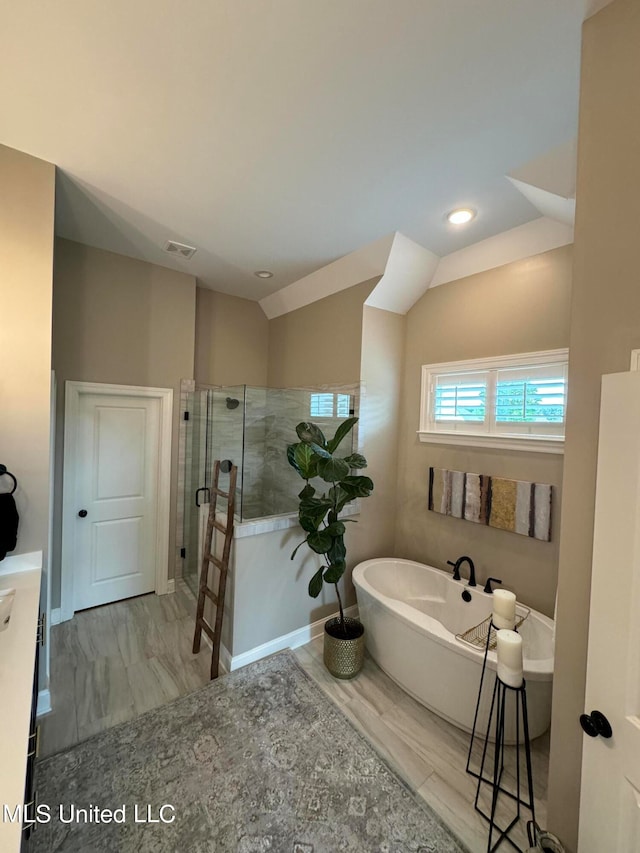 bathroom with vanity, vaulted ceiling, and plus walk in shower