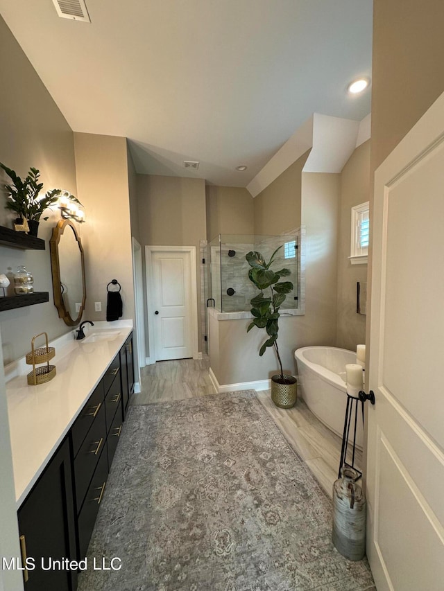 bathroom featuring vanity, hardwood / wood-style floors, plus walk in shower, and lofted ceiling