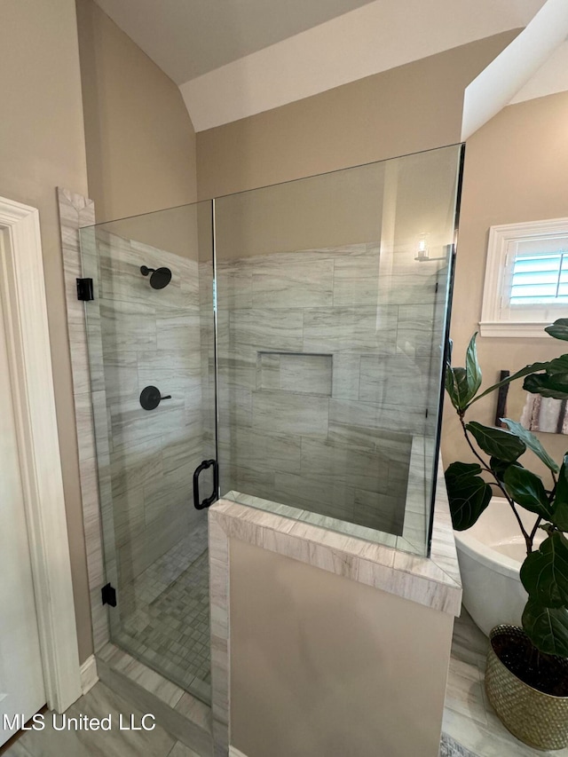 bathroom with vaulted ceiling, independent shower and bath, and wood-type flooring