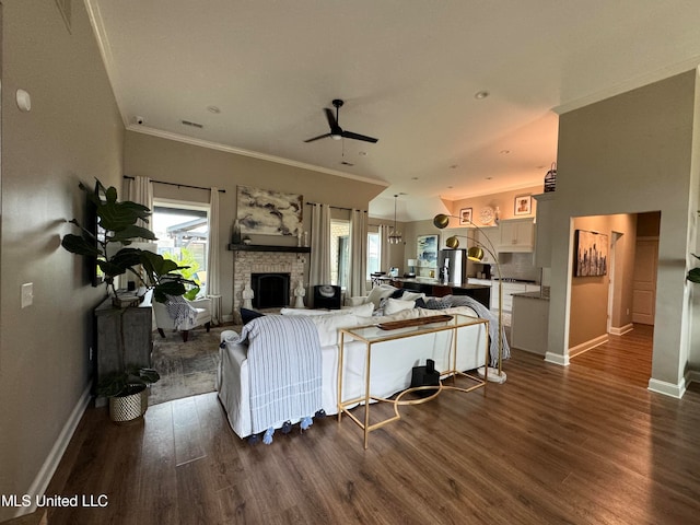 living room with crown molding, a fireplace, dark wood-type flooring, and plenty of natural light