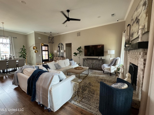 living room featuring ornamental molding, a wealth of natural light, ceiling fan with notable chandelier, and dark hardwood / wood-style flooring