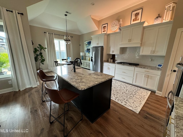 kitchen featuring stainless steel fridge, dark hardwood / wood-style flooring, an island with sink, decorative light fixtures, and sink