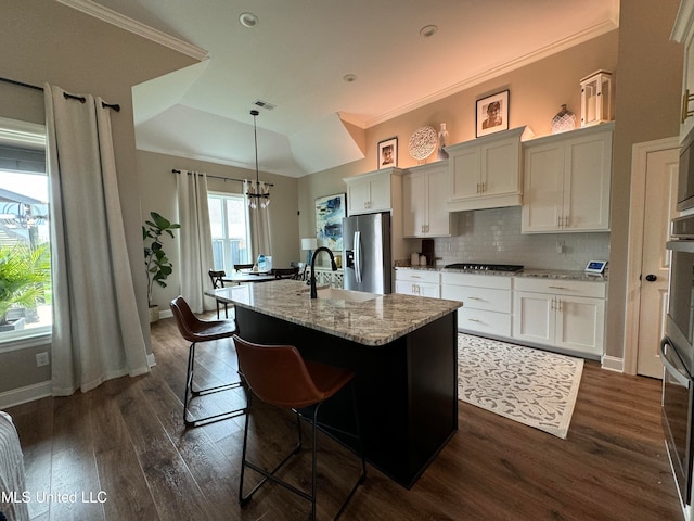 kitchen with dark hardwood / wood-style floors, an island with sink, stainless steel fridge with ice dispenser, decorative light fixtures, and white cabinets