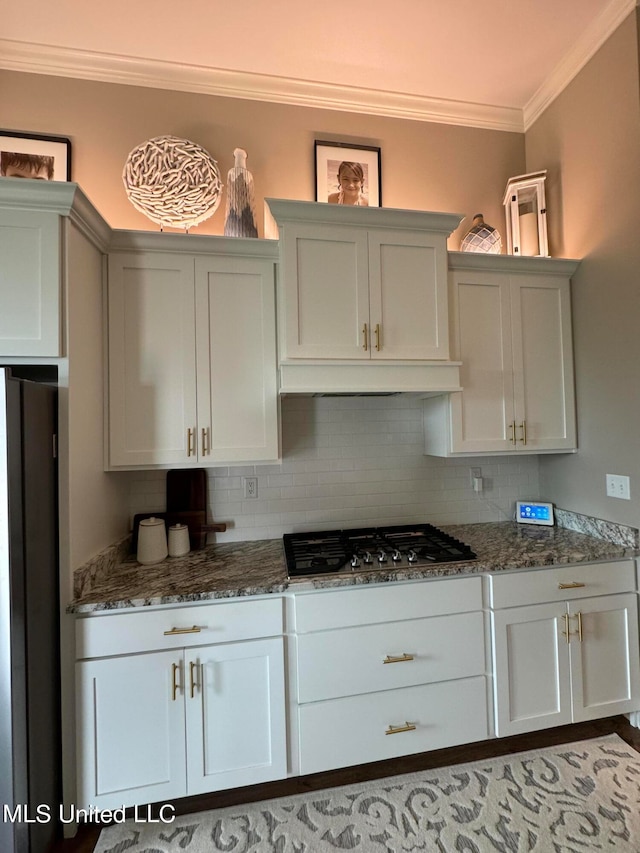 kitchen featuring appliances with stainless steel finishes, white cabinets, ornamental molding, and tasteful backsplash