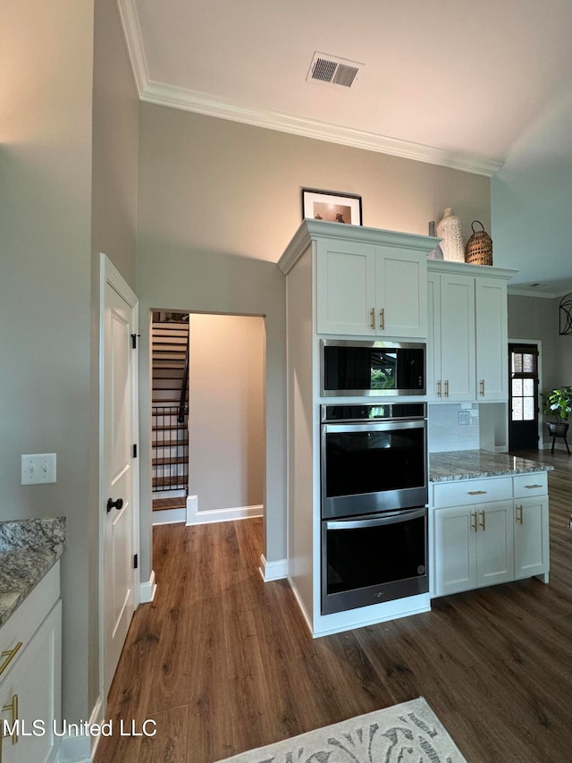 kitchen with white cabinets, light stone countertops, stainless steel appliances, and dark hardwood / wood-style floors