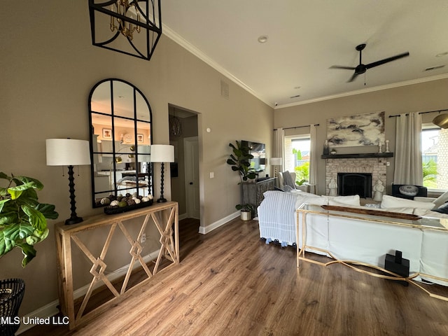 living room with crown molding, wood-type flooring, a fireplace, and ceiling fan