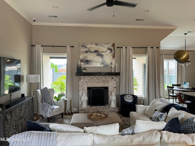 living room featuring crown molding, a stone fireplace, and ceiling fan