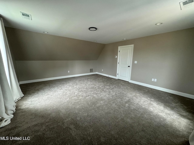 additional living space featuring dark carpet and vaulted ceiling