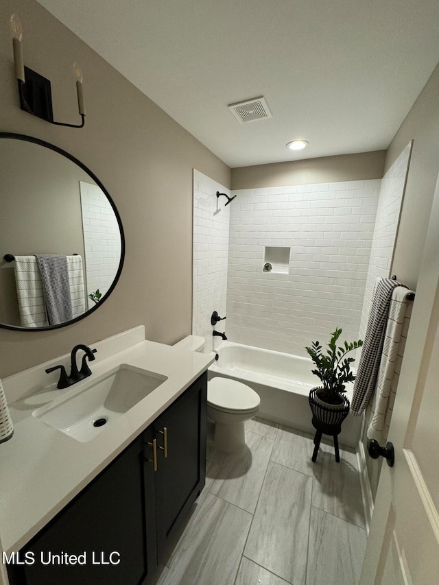 full bathroom featuring tiled shower / bath, vanity, and toilet