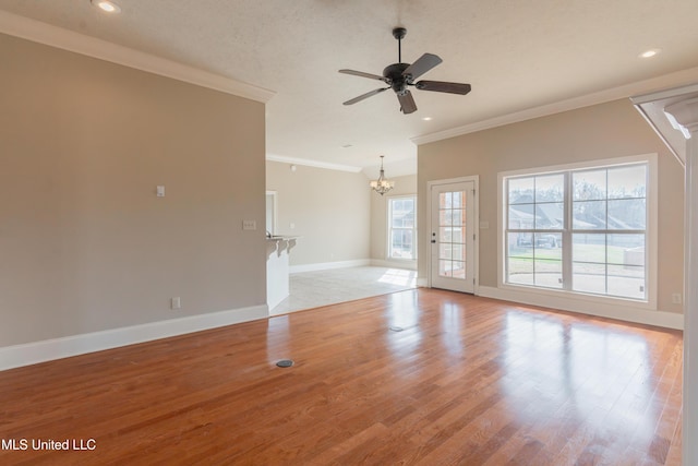 unfurnished living room featuring crown molding, ceiling fan with notable chandelier, and light hardwood / wood-style flooring