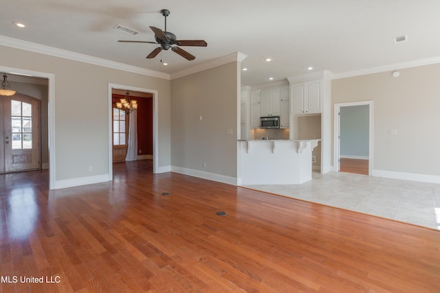 unfurnished living room featuring ceiling fan with notable chandelier, light hardwood / wood-style flooring, and ornamental molding