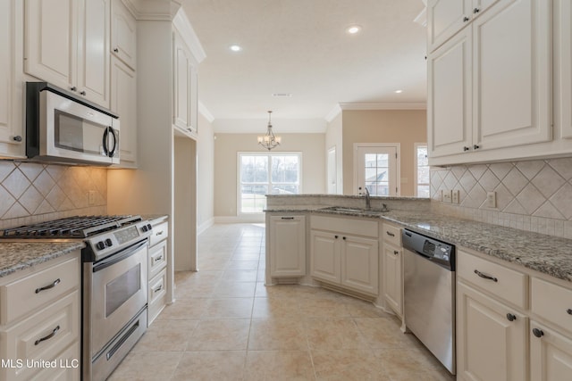 kitchen with sink, appliances with stainless steel finishes, white cabinetry, light stone counters, and ornamental molding