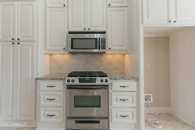 kitchen with light stone countertops, decorative backsplash, stainless steel appliances, and white cabinets