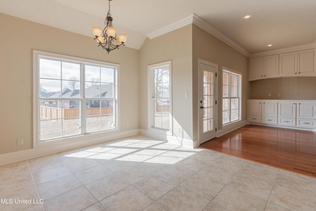 unfurnished dining area featuring an inviting chandelier, lofted ceiling, ornamental molding, and light tile patterned flooring