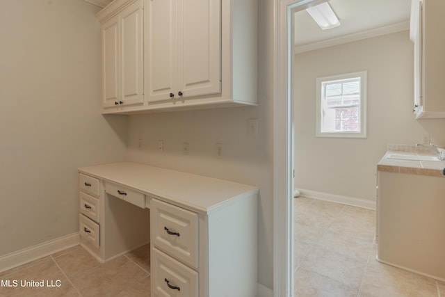 unfurnished office featuring crown molding, built in desk, sink, and light tile patterned floors