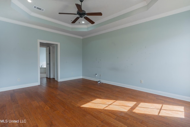 empty room featuring wood-type flooring, ornamental molding, a raised ceiling, and ceiling fan