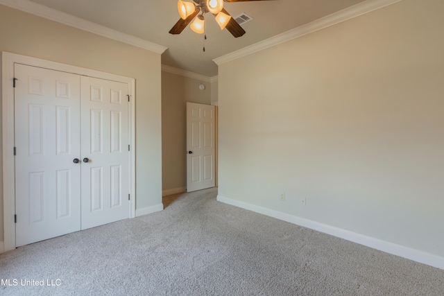 unfurnished bedroom with crown molding, light colored carpet, ceiling fan, and a closet