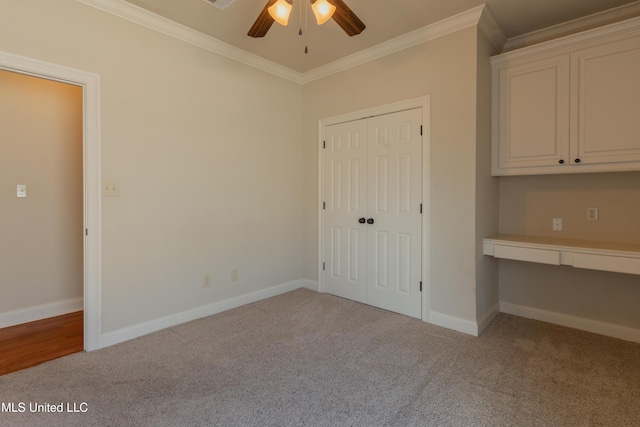 unfurnished bedroom with crown molding, built in desk, and light carpet