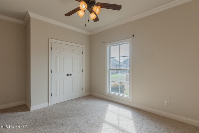 unfurnished bedroom featuring crown molding, carpet floors, a closet, and ceiling fan