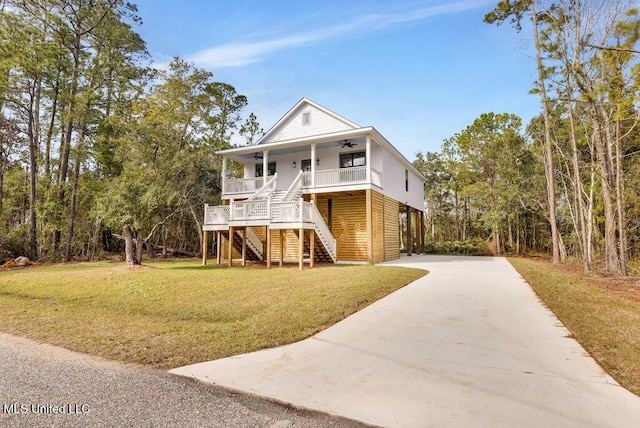 coastal inspired home with driveway, stairway, a porch, and a front yard