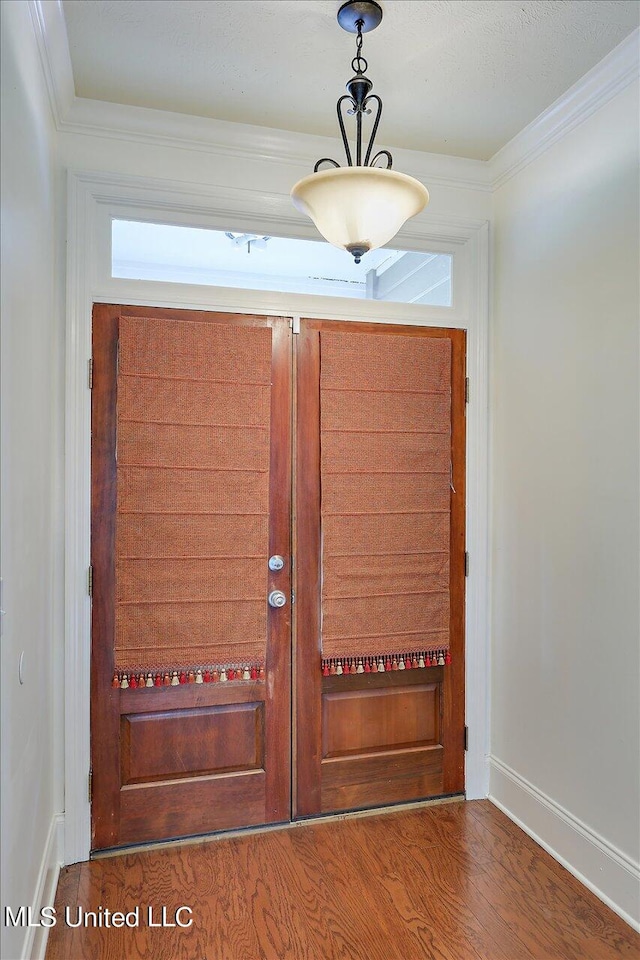 entryway with ornamental molding and hardwood / wood-style floors