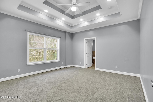 spare room with baseboards, a raised ceiling, carpet, and crown molding